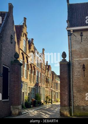 Charmante vue sur Hofstraat à Dordrecht avec des maisons historiques en briques, rue pavée et lumière chaude du soleil créant une atmosphère paisible de la vieille ville hollandaise a Banque D'Images