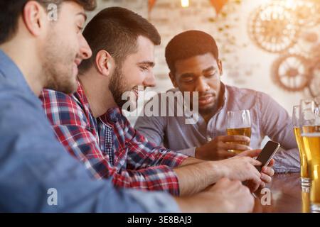 Réunion d'amis. Man Showing Photos sur smartphone Banque D'Images