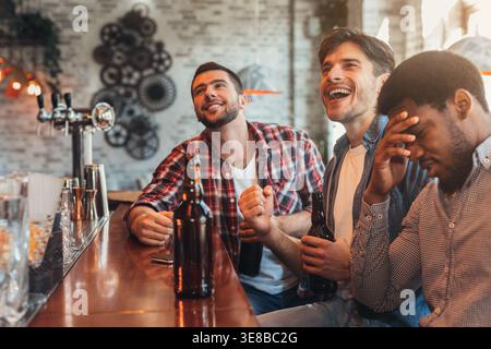 Hommes regardant un match de football dans un bar sportif Banque D'Images
