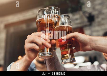 Amis toast avec des verres de bière au pub Banque D'Images