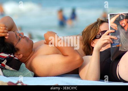 Un jeune couple se détend et lit un magazine sur la plage d'Ocean Grove, New Jersey, sur la côte du Jersey en été Banque D'Images
