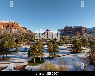 Terrain de golf enneigé avec pins et montagnes de roches rouges à Sedona Arizona sous ciel bleu clair d'hiver. Banque D'Images