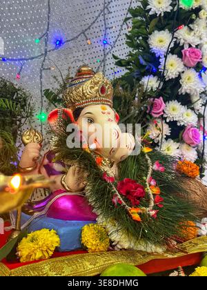 Ganpati Idol avec guirlandes florales et offres traditionnelles. Gros plan détaillé d'une statue de Ganesha placée sur un autel décoré avec des fleurs de souci. Banque D'Images