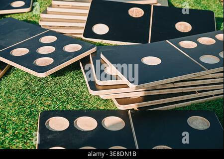 Gros plan de carreaux de domino en bois surdimensionnés dispersés sur l'herbe verte, idéal pour les jeux de plein air, les activités familiales et les concepts de loisirs. Visuel parfait f Banque D'Images