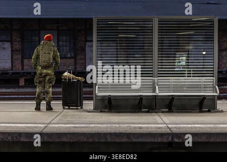 Homme militaire en uniforme sur la plate-forme de la station de nuit. L'homme se tient près des bancs avec ses bagages. Banque D'Images