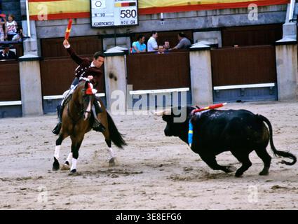 Un toreros à cheval fait face à un taureau dans une arène à Madrid. La foule regarde le déroulement du combat. Banque D'Images