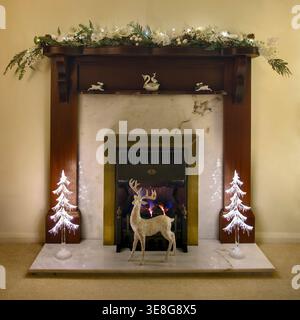 Cheminée de Noël symétrique avec arbres décoratifs éclairés, guirlande festive et feu lumineux dans un intérieur confortable du salon Banque D'Images