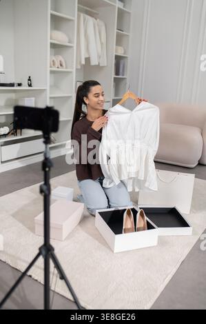Jolie femme vlogger de mode présentant une nouvelle collection de mode en ligne et regardant excité Banque D'Images