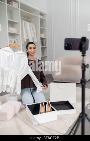Jolie femme vlogger de mode présentant une nouvelle collection de mode en ligne et regardant excité Banque D'Images