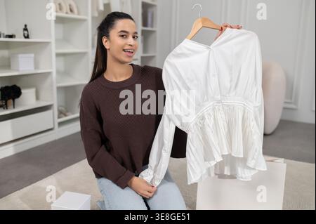 Jolie femme vlogger de mode présentant une nouvelle collection de mode en ligne et regardant excité Banque D'Images