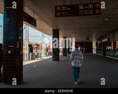 Passager marchant sous les panneaux de quai à la gare de Balti Jaam à Kalamaja, Tallinn, Estonie, début du printemps Banque D'Images