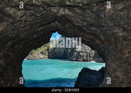 Arc rocheux naturel encadrant une mer méditerranée turquoise vibrante et des falaises de calcaire escarpées sous un ciel bleu clair dans un cadre de grottes côtières. Banque D'Images
