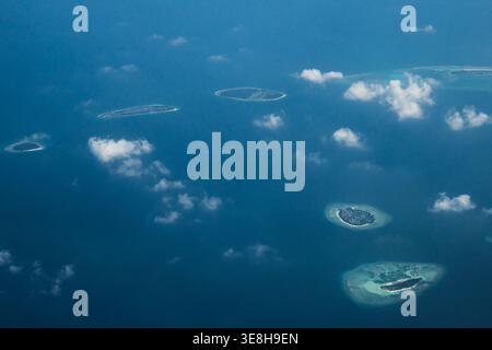 Vue aérienne d'îles éparpillées ressemblant à des joyaux au milieu de la vaste étendue bleu profond, bordée par la dentelle blanche des vagues brisées, Flight from Malé to Hani Banque D'Images