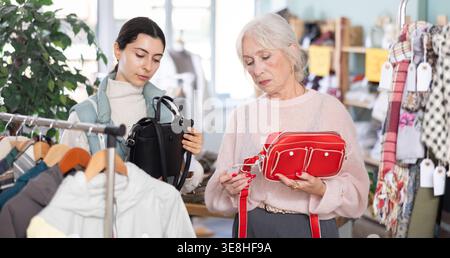 Mère âgée et sa fille adulte choisissent ensemble des sacs à main à la mode dans le magasin de vêtements Banque D'Images