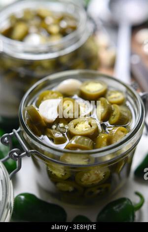 Gros plan du pot rempli de tranches de jalapeno marinées dans la saumure. Texture de piment vert préservée avec graines et liquide Banque D'Images