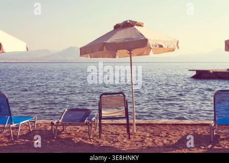 Plage vide avec parasols et chaises longues donnant sur la mer en Grèce Banque D'Images