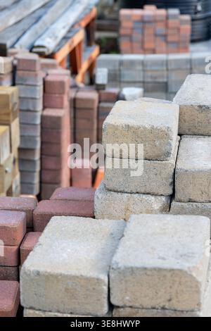Pavés et briques empilés sur un chantier de construction, prêts pour l'aménagement paysager et la construction Banque D'Images