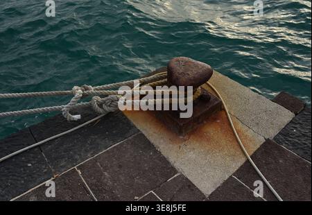 Borne d'amarrage rouillée avec corde sur la jetée du front de mer à Ortigia, Sicile Banque D'Images