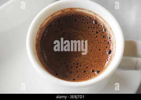 Tasse de café turque sur une table avec un liquide sombre riche à l'intérieur Banque D'Images