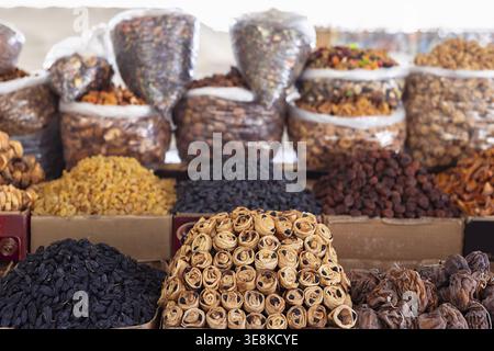 Fruits séchés et noix à l'étal coloré du marché en gros plan. Pommes farcies rouleaux avec raisins secs, tas de raisins secs, abricots séchés dattes pruneaux amandes dans des sacs. Banque D'Images