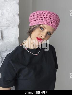 Portrait de belle femme en béret noir et T-shirt dans le style français. Maquillage brillant avec rouge à lèvres rouge. Photo verticale. Banque D'Images