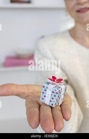 Mains de femme tenant la boîte-cadeau avec l'arc rouge, gros plan. Photo verticale. Banque D'Images