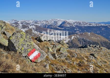 Marqueur de sentier de randonnée alpin sur une montagne rocheuse guidant les randonneurs à travers un paysage alpin accidenté avec des sommets enneigés Banque D'Images