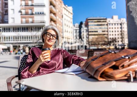 Femme mature profitant de la pause café dans le café de la ville Banque D'Images