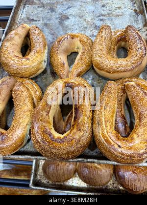 Bagels fraîchement cuits avec des graines de sésame sur des plaques de cuisson dans un cadre de boulangerie. Photo mobile Banque D'Images