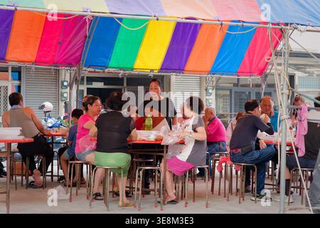 Taichung, Taiwan - 26 mai 2024 : banquet bando en plein air sous une canopée arc-en-ciel lors d'un festival du temple, mettant en valeur la gastronomie commune et la tradition culturelle. Banque D'Images