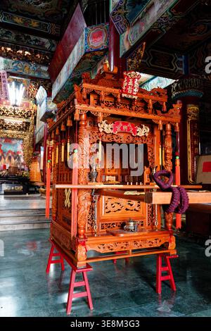 Taichung, Taiwan - 26 mai 2024 : palanquin en bois sculpté avec des pompons rouges à l'intérieur du temple Gaomei Wenhsin, prêt pour une procession de la divinité Wang Ye. Banque D'Images