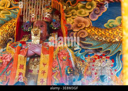 Taichung, Taïwan - 26 mai 2024 : statue de Mazu au temple Gaomei Xi'an Chaotian avec couronne dorée, robes de cérémonie oranges et phénix en toile de fond. Banque D'Images