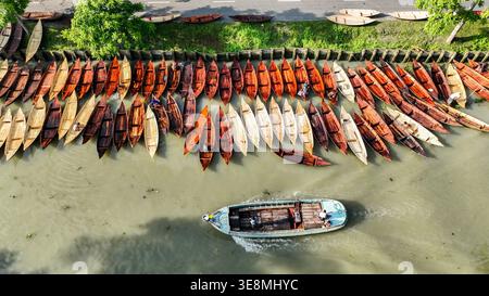 Vue aérienne de nombreux petits bateaux en bois, certains avec des gens, alignés le long d'une rive contrastant avec l'eau, Pirojpur Pourashava, Barisal Divi Banque D'Images