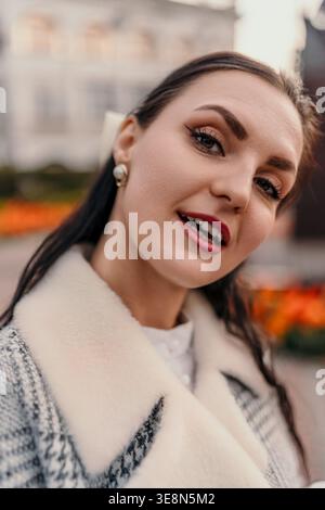 Femme souriant portrait d'une dame élégante portant un manteau en tweed avec col en fausse fourrure blanche à l'extérieur pendant l'heure d'or Banque D'Images