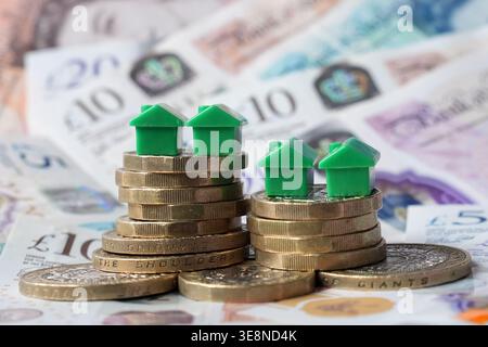 SOUS EMBARGO À 0001 JEUDI 16 AVRIL dossier photo datée du 29/07/25 de maisons modèles sur une pile de pièces de monnaie et de billets de banque. Les loyers moyens demandés en dehors de Londres sont restés au point mort dans les premiers mois de 2026, marquant la première fois depuis 2017 qu’ils n’ont pas augmenté entre la fin d’une année précédente et le début d’une nouvelle année, selon un indice. Date d'émission : jeudi 16 avril 2026. Banque D'Images