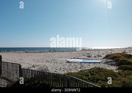 Vue ensoleillée sur la plage de Carnon près de Montpellier avec une voile de planche à voile sur le sable, les dunes côtières et les gens profitant de la mer Méditerranée, Hérault, France. Banque D'Images