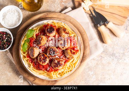 Une assiette de spaghettis classiques garnie de boulettes de viande dorées et d'une riche sauce tomate sur un plat en céramique légère. Banque D'Images