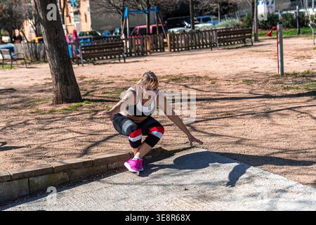 Femme senior exerçant à l'extérieur faisant des squats dans le parc Banque D'Images