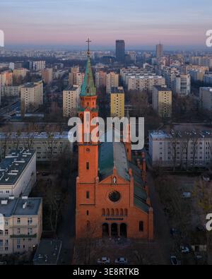 Vue aérienne de l'église historique en briques rouges de Augustine avec sa grande flèche verte entourée d'immeubles urbains au crépuscule à Varsovie, Mas Banque D'Images