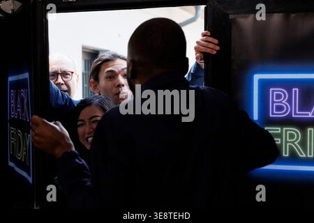 Folie du Black Friday. Foule de frénésie divers clients poussent l'agent de sécurité et s'introduisent par effraction dans le centre commercial, les chasseurs de bargan devenant fous pour se rendre au magasin de détail en premier afin d'obtenir les meilleures offres Banque D'Images