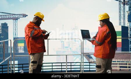 Travailleur offshore de plate-forme sur les opérations de surveillance de plate-forme pétrolière avec ordinateur portable logiciel. Expert en équipement de forage examinant les opérations énergétiques à l'aide d'un ordinateur portable, prévoyant les pannes d'équipement, Banque D'Images
