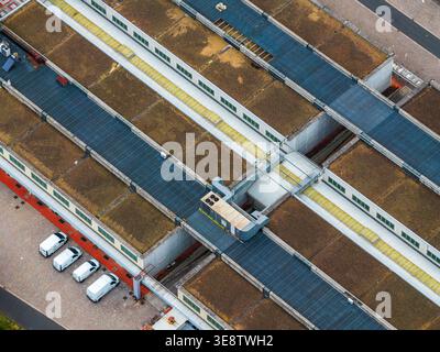 Vue aérienne du toit du bâtiment industriel moderne avec des sections vertes de sedum et des fourgonnettes blanches garées à côté à Leccio, Toscane, Italie. Banque D'Images