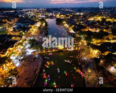 Vue aérienne de la ville antique de Hoi an la nuit avec des bateaux lanternes colorés sur la rivière Thu bon et des bâtiments historiques illuminés à Hoi an, Vietnam. Banque D'Images