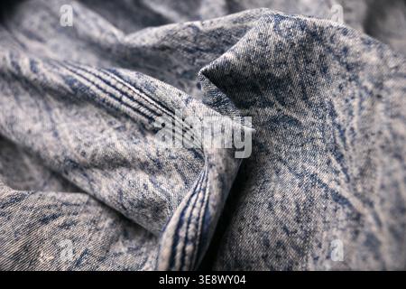 Chemise en denim bleu clair et blanc cassé Macro — gros plan sur le bouton en acier, la texture froissée et les arrière-plans flou doux Banque D'Images