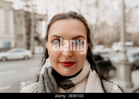 Femme portrait rouge à lèvres jeune femme portant rouge à lèvres rouge et foulard à carreaux dans une rue animée de la ville avec arrière-plan flou bokeh Banque D'Images