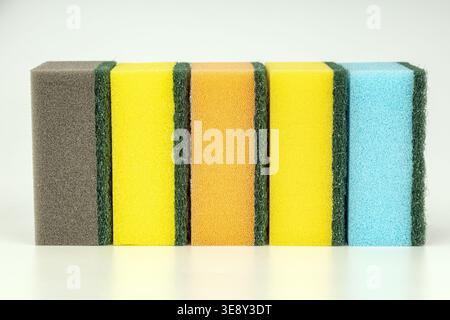 Collection organisée de six éponges colorées de nettoyage de cuisine équipées de tampons à récurer abrasifs verts. Comprend gris, jaune vif, orange et L. Banque D'Images
