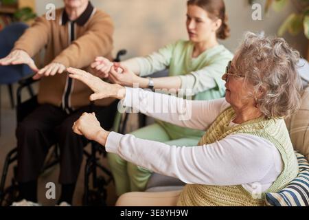 Femmes âgées et homme exerçant avec une soignante dans une maison de soins infirmiers, favorisant la mobilité, la réadaptation, le vieillissement actif Banque D'Images