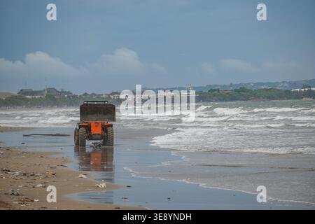 Machinerie lourde nettoyage des débris d'une plage tropicale Banque D'Images