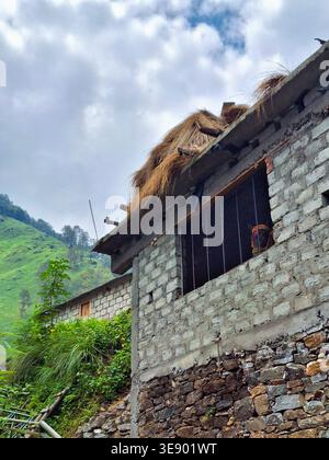 Une maison traditionnelle en pierre avec un toit de chaume est nichée dans la colline du temple Madmaheshwar, Uttarakhand, Inde. La maison dispose d'un simple pourtant Banque D'Images