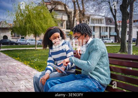 Deux jeunes amis adultes pointant une tablette numérique Banque D'Images